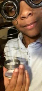Person wearing spiral metal glasses and white shirt holding coiled metal spring or coil object